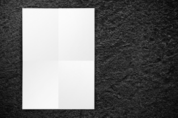 Black folded White paper poster hanging at black stone wall,Temp