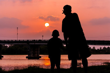Fototapeta na wymiar silhouette of father and son point look at to sunset at the river 