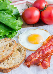 Making open face sandwich with egg, bacon, tomato and lettuce