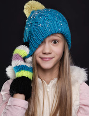 Girl wearing winter hat and gloves covered with snow flakes - winter clothes