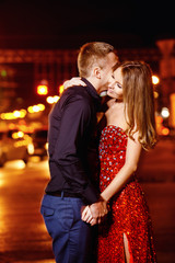 Closeup portrait of beautiful young couple kissing at night city
