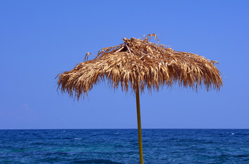 Fototapeta na wymiar Beach umbrella by the sea on the island of Rhodes.