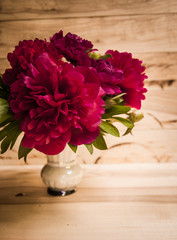 Floral frame with pink peonies on wooden background