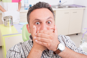 Scared man at dentist covering his mouth