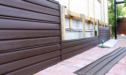 Installation of brown plastic siding on the facade