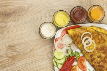 Scrambled egg omelet with vegetables on a wooden table. Preparation of fast food home.
