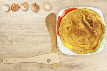 Scrambled egg omelet on a wooden table. A plate of food.
