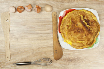 Scrambled egg omelet on a wooden table. A plate of food.
