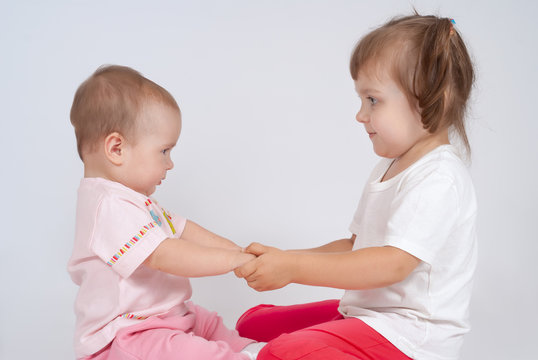 Playing children. Two little sisters are holding hands. Friendship and love.