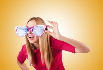 Tall model with giant sunglasses against the gradient