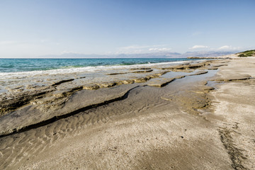 Shore of Ionian sea with flat rocks on the beach