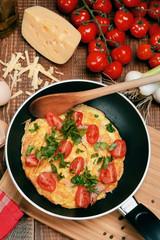Omelette with ham, tomatoes and chees on the frying pan.