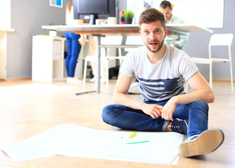 Handsome designer sit in his office with colleagues discussing