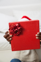 Black man covering his face with gift