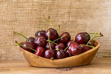 cherries in bowl of olive wood with jute background