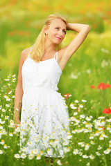 Naklejka na ściany i meble Pregnant happy woman in a flowering poppy field outdoors
