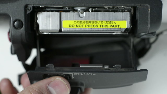 A mini DV camera deck with the tape being ejected, and reinserted.