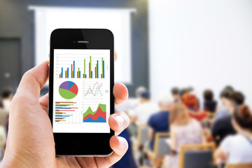 Close-up hand holding mobile phone with analyzing graph