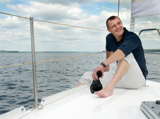 a young guy sitting on the deck of a yacht