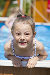 Child girl in blue bikini near swimming pool. Hot Summer