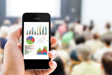 Close-up hand holding mobile phone with analyzing graph
