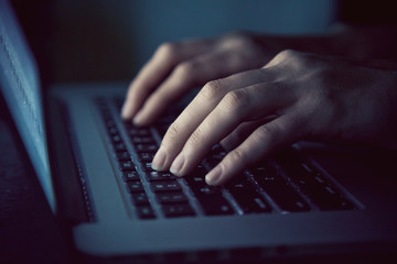 hands with laptop typing in night