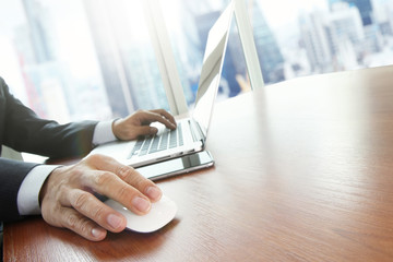 Close up of male hands on mouse and over black keyboard of lapto