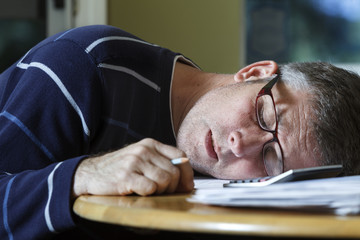 Man sleeping with head on paperwork.