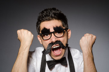 Obraz premium Young man with false moustache isolated on gray
