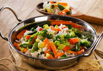 Rice with vegetables on a wooden background.