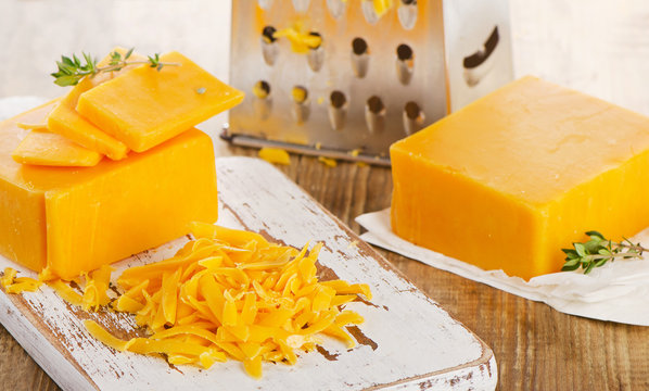 Grated Cheddar Cheese on  a wooden Cutting Board.