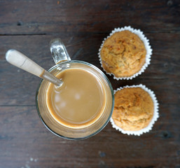 Hot coffee with two banana cupcakes on timber table