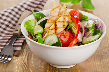 Salad with grilled chicken in  white bowl.