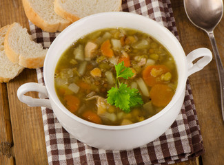 Soup with Lentils, Beans, Chicken and Vegetables on a rustic woo