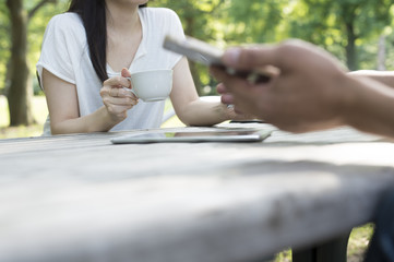 Men and women are using the smartphone face to face in the garden