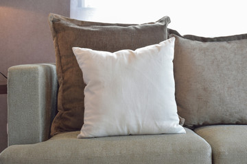 White, brown and grey velvet pillows setting up on sofa in livin