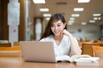 Asian beautiful female student study in library with laptop