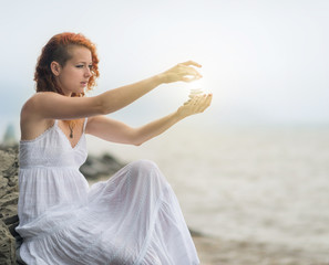 Portrait of redhead woman holding zen stones in hand. With sunshine effect.