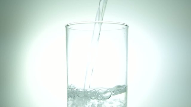 Water being poured into a clean clear glass against a bright white background