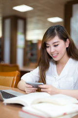 Asian beautiful female student study in library with laptop