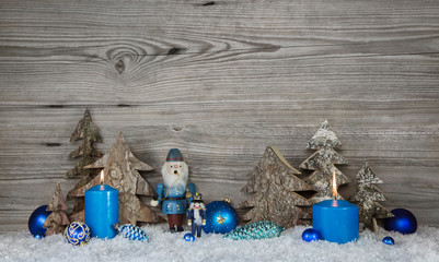 Holz Hintergrund zu Weihnachten mit Dekoration in grau, weiß und blau mit Nußknacker und Kerze