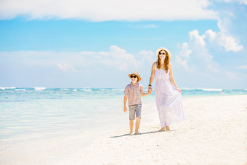 Mother and son walk along the white sand beach having great