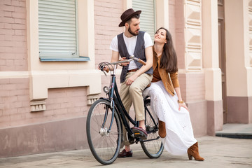 Fototapeta premium Young couple sitting on a bicycle against the wall 