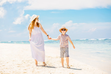 Mother and son walk along the white sand beach having great