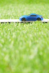 緑の草原を走る青いスポーツカー