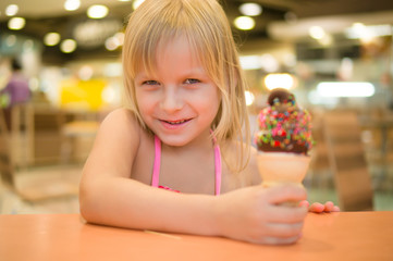 Adorable girl eat chocolate ice cream with sprinkles in mall