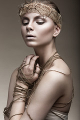 Beautiful girl with a bronze skin, pale makeup and unusual accessories. Art beauty image. Beauty face. Picture taken in the studio.