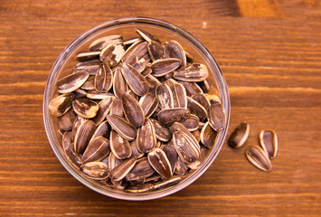 Sunflower seeds on bowl on wooden table seen from above
