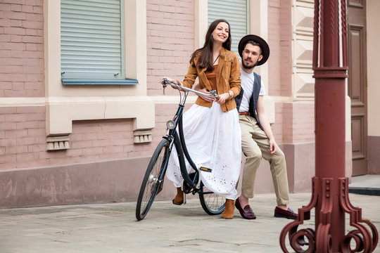 Young couple sitting on a bicycle against the wall 