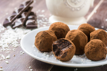 Homemade healthy vegan chocolate truffles with dates, coconut flakes and rolled oats served on white plate